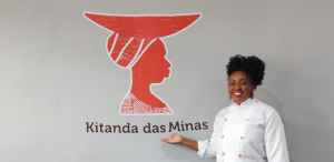 Chef de cozinha aponta para lodo escrito "Kitanda das Minas"