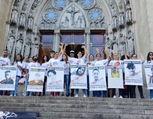 Mulheres seguram cartazes com os punhos erguidos