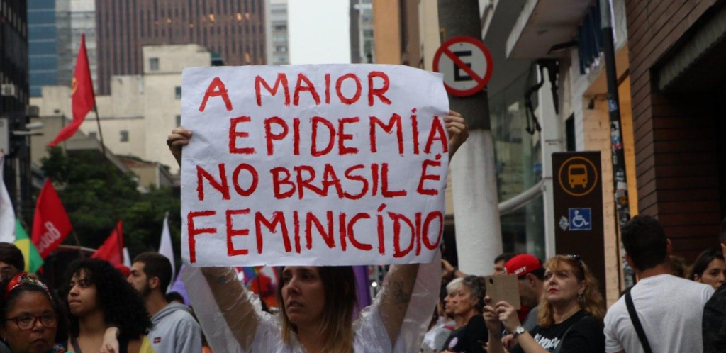 Foto mostra mulher segurando um cartaz com o texto a maior epidemia no Brasil é o feminicídio