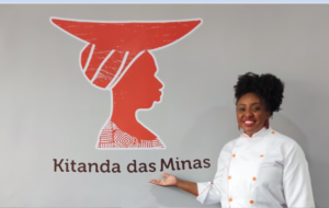 chef de cozinha aponta para logo do Kitanda das Minas