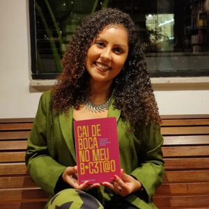 Foto mostra Tamiris Coutinho segurando seu livro "ai de boca no meu b#c3t@o: o funk como potência do empoderamento feminino"
