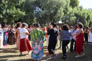 Várias mulheres em círculo em um jardim com árvores ao fundo