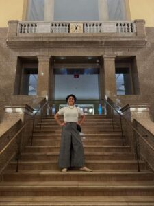 Mulher de camisa branca e calça cinza escuro nas escadas da Suprema Corte dos sua