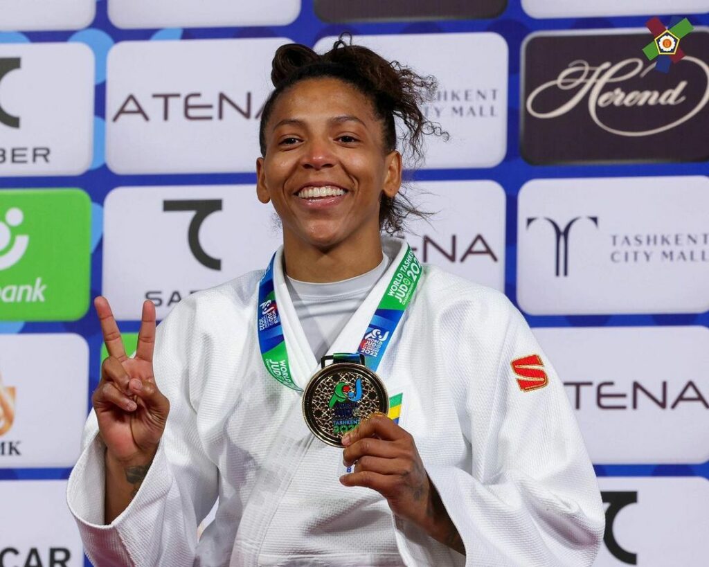 mulher com traje de judô segurando uma medalha