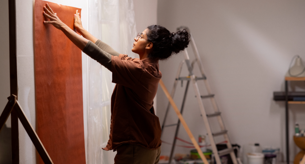 mulher colando papel de parede. Decorações e reformas