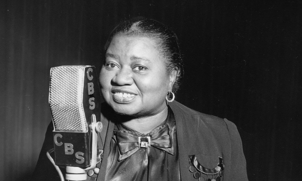 Foto em preto e branco mostra Hattie McDaniel segurando microfone