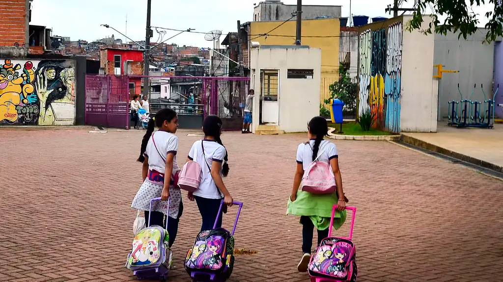 três meninas carregando mochila de rodinhas