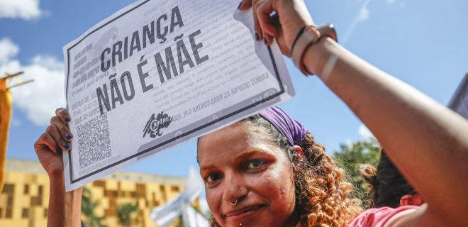 Foto mostra mulher negra segurando cartaz em manifestação relacionada ao aborto legal