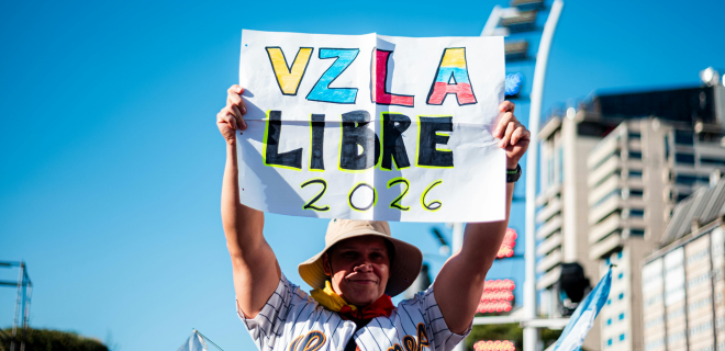 Foto mostra mulher com um cartaz escrito Venezuela Libre 2026
