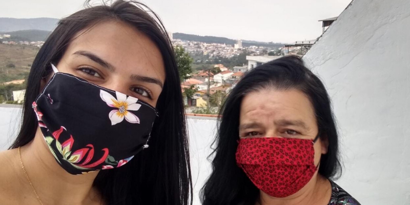 Duas mulheres de máscara olham para câmera