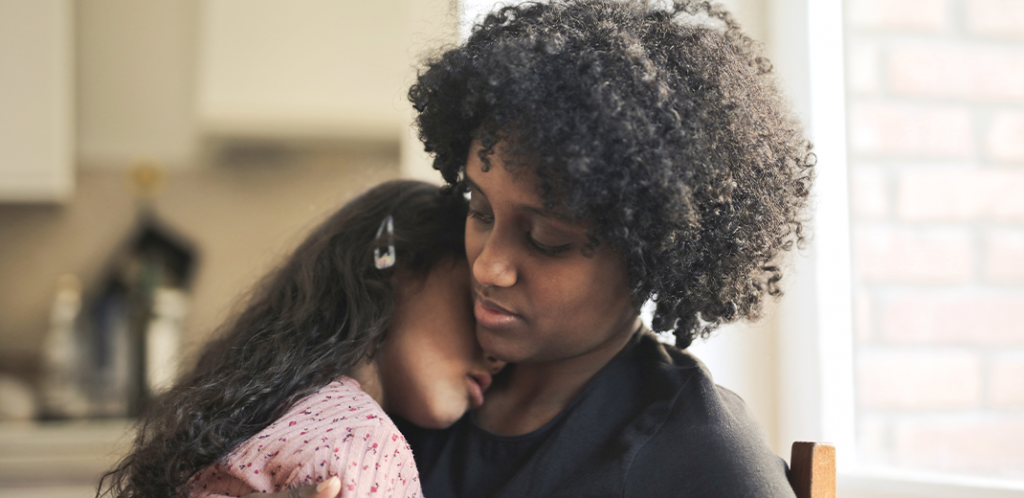 Foto mostra mãe negra abraçando criança