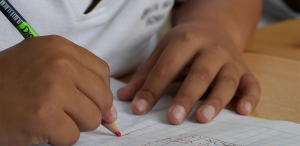 Foto, que representa a educação brasileira, mostra criança escrevendo em caderno