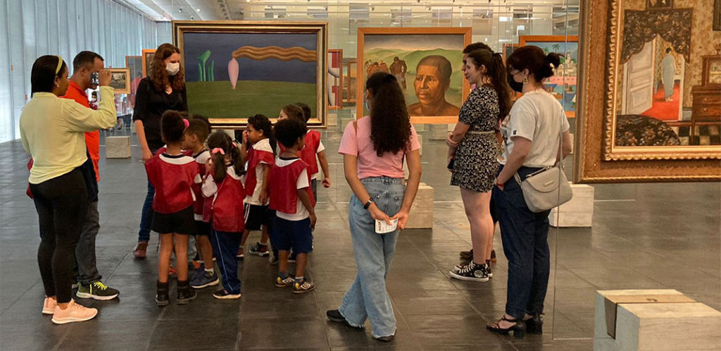 Foto mostra as crianças apresentando a obra Figura Só, de Tarsila do Amaral para os visitantes do museu