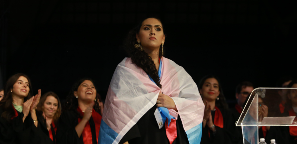 Mulher envolta da bandeira trans