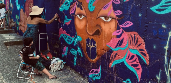 Foto mostra Laís gestante grafitando parede com os filhos