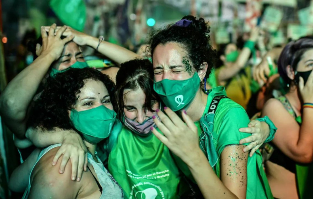 Foto mostra mulheres argentinas, com lenços do movimento pró-aborto, comemorando descriminalização do aborto no país
