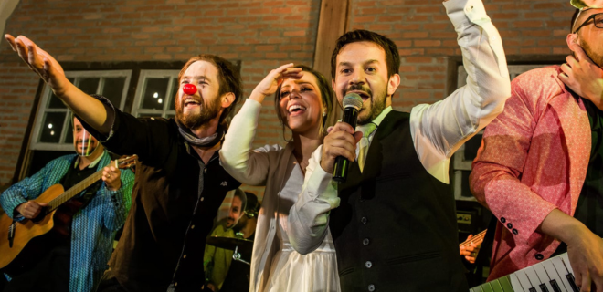 Foto do casamento de Priscilla e Fernando, que se conheceram por causa do carnaval, mostra a banda Estrambelhados cantando no casamento
